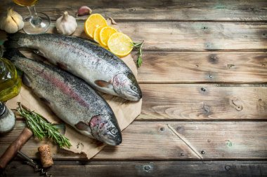 Limon dilimleri ve güzel kokulu biberiye ile eski kağıt üzerinde ham deniz balık somon. Ahşap arka plan üzerinde