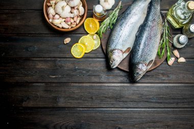 Otlar, baharatlar ve limon dilimleri ile çiğ balık somon. Ahşap bir arka plan üzerinde.