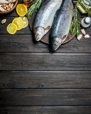 Otlar, baharatlar ve limon dilimleri ile çiğ balık somon. Ahşap bir arka plan üzerinde.