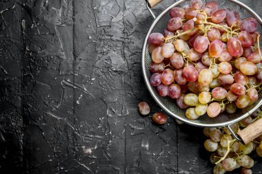 White grapes in a saucepan. On black rustic background.