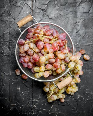 White grapes in a saucepan. On black rustic background.