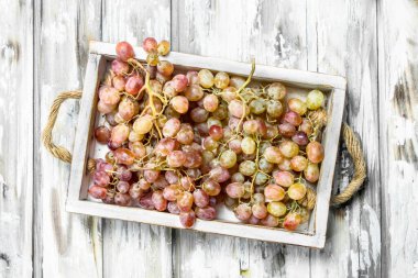 Kutuda pembe üzümler var. Rustik bir arka plan üzerinde.