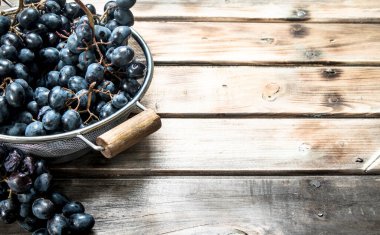 Tencerede siyah üzüm. Ahşap bir arka plan üzerinde.