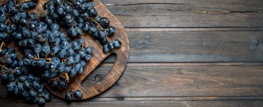 Olgun siyah üzümler. Ahşap bir arka plan üzerinde.