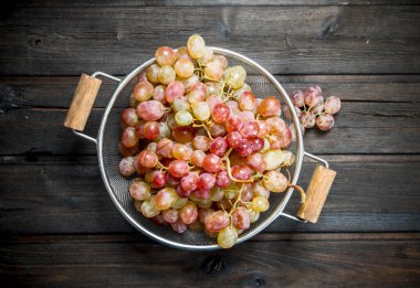 White grapes in a saucepan. On a wooden background.