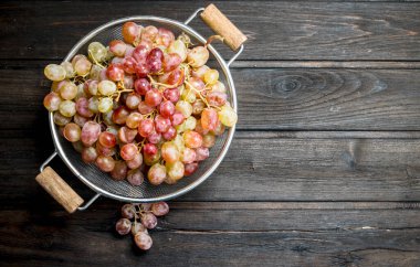 White grapes in a saucepan. On a wooden background.