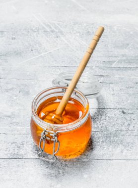 Doğal bal kavanozuna tahta kaşıkla. Rustik bir arka plan üzerinde.