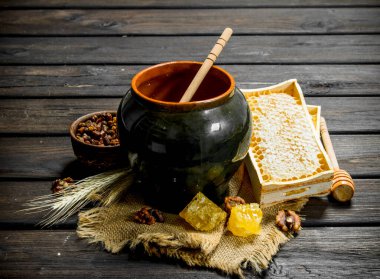 Bir kaşık ile bir tencerede doğal tatlım. Ahşap bir arka plan üzerinde.