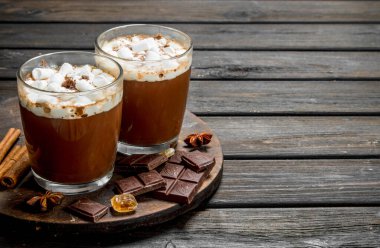 Sıcak çikolata şekerleme ve güzel kokulu tarçın ile kupalar içinde. Ahşap bir arka plan üzerinde.