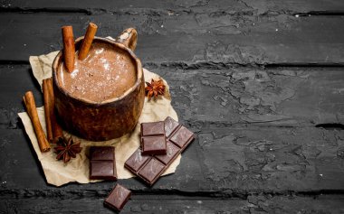 Sıcak çikolata tarçın ile sopa. Rustik siyah arka plan üzerine.