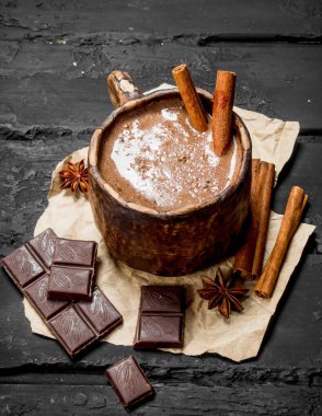 Sıcak çikolata tarçın ile sopa. Rustik siyah arka plan üzerine.