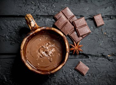 Sıcak çikolata tarçın ile sopa. Rustik siyah arka plan üzerine.