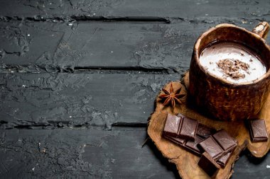 Sıcak çikolata tarçın ile sopa. Rustik siyah arka plan üzerine.