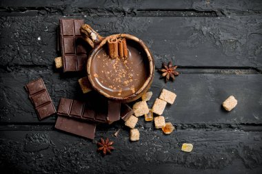 Sıcak çikolata tarçın ile sopa. Rustik siyah arka plan üzerine.