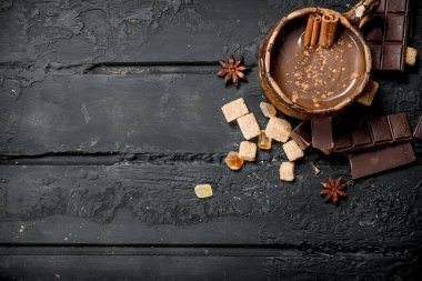 Sıcak çikolata tarçın ile sopa. Rustik siyah arka plan üzerine.