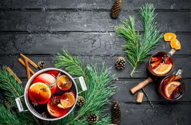 Çam dalları ve koniler mulled şarap. Rustik siyah arka plan üzerine.