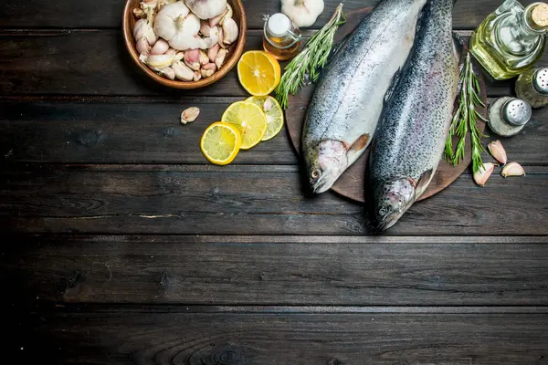 Otlar, baharatlar ve limon dilimleri ile çiğ balık somon. Ahşap bir arka plan üzerinde.