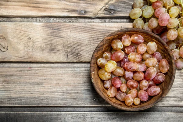 Kasede pembe üzümler. Ahşap bir arka plan üzerinde.