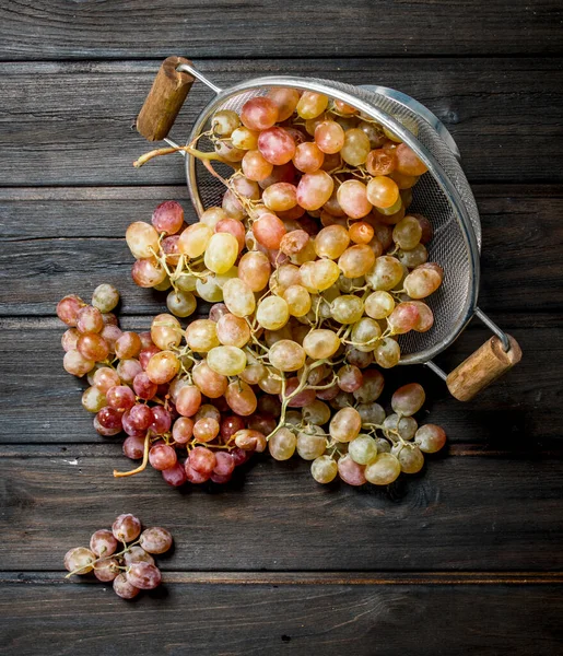 White grapes in a saucepan. On a wooden background.