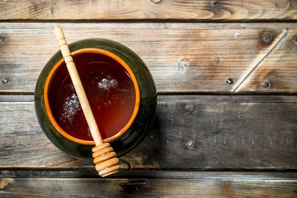 スプーンで鍋に蜂蜜します 木製の背景に — ストック写真