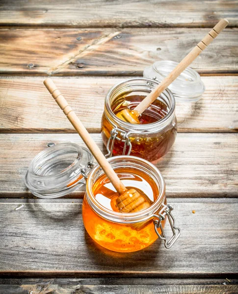 用勺子把新鲜蜂蜜放在玻璃瓶里 在木制背景 — 图库照片