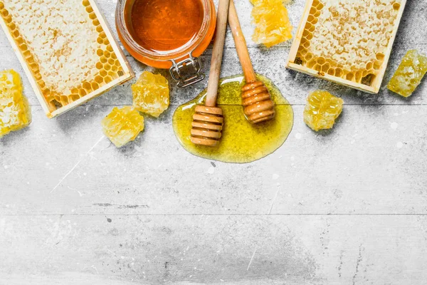 Peteğin tahta kaşıklar ile doğal bal. Rustik bir arka plan üzerinde.