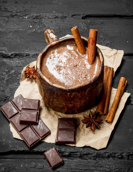 Sıcak çikolata tarçın ile sopa. Rustik siyah arka plan üzerine.