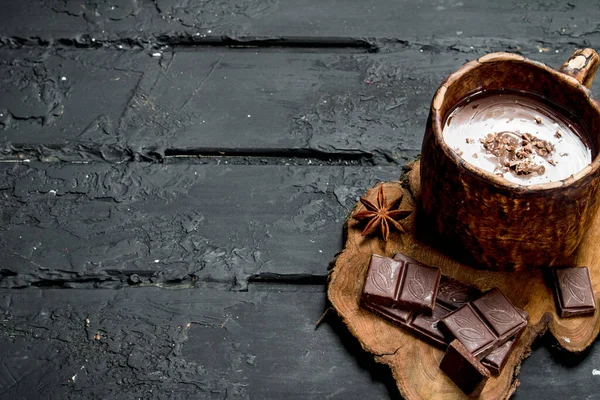Sıcak çikolata tarçın ile sopa. Rustik siyah arka plan üzerine.