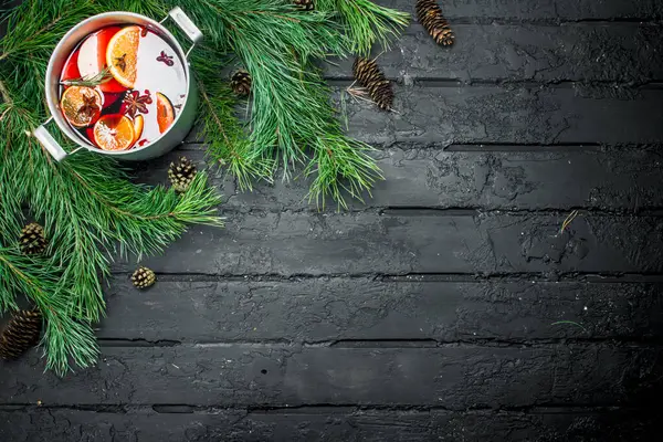 Çam dalları ve koniler mulled şarap. Rustik siyah arka plan üzerine.