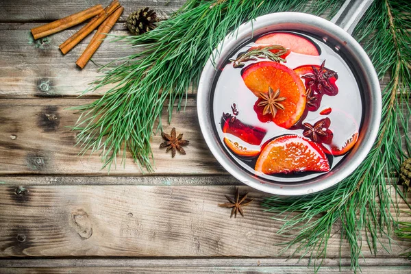 stock image Mulled wine in a pot of spices. On a wooden background.