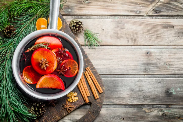 stock image Mulled wine in a pot of spices. On a wooden background.