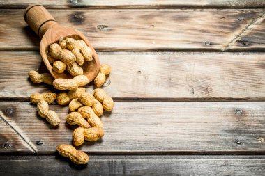 Tahta bir kepçede yer fıstığı. Ahşap arka planda.