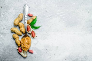 Bir kaşık yeşil yaprakları ile fıstık ezmesi. Rustik bir arka plan üzerinde.