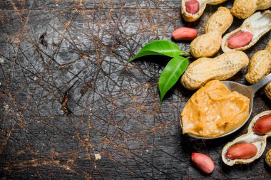 Yaprakları bir kaşıkla fıstık yağı. Ahşap bir arka plan üzerinde.