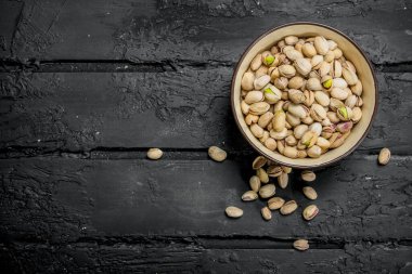 Antep fıstığı kabın içinde. Rustik siyah arka plan üzerine.