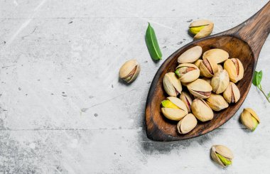 Antep fıstığı yaprakları bir tahta kaşıkla içinde. Rustik bir arka plan üzerinde.