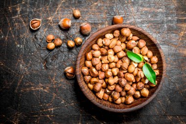 Kabuklu Fındık yaprakları bir kase ile. Ahşap bir arka plan üzerinde.