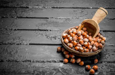 Ahşap bir kepçe ile bir kase fındık. Rustik siyah arka plan üzerine.