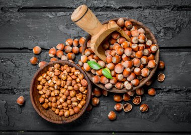 Ahşap bir kepçe ile bir kase fındık. Rustik siyah arka plan üzerine.