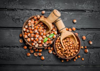 Ahşap bir kepçe ile bir kase fındık. Rustik siyah arka plan üzerine.