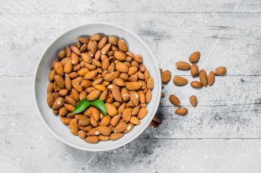 Yeşil yaprakları ile bir kapta Badem . Rustik bir arka plan üzerinde.