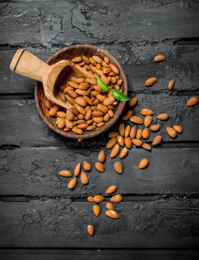 Badem ahşap kepçe ile kase. Rustik siyah arka plan üzerine.