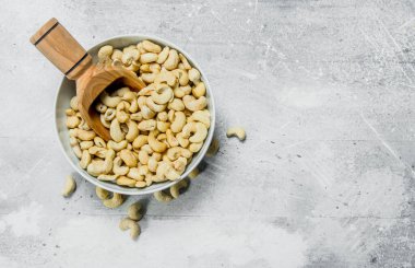 Bir kepçe ile bir kase içinde kaju fıstığı. Rustik bir arka plan üzerinde.