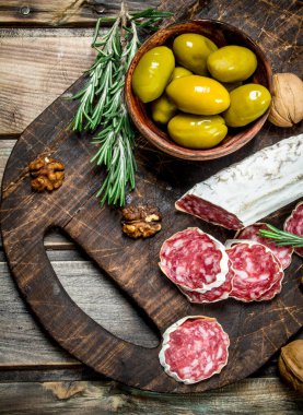 Salam zeytin ve biberiye bir delikanlı. Ahşap bir arka plan üzerinde.