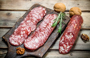 Biberiye ve ceviz ile dilimlenmiş salam. Ahşap bir arka plan üzerinde.