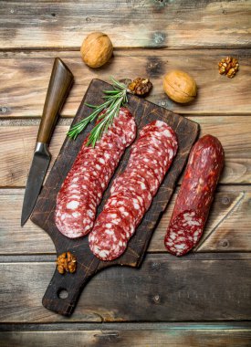 Biberiye ve ceviz ile dilimlenmiş salam. Ahşap bir arka plan üzerinde.