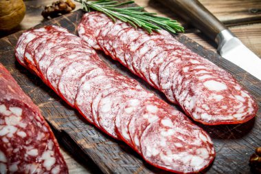 Biberiye ve ceviz ile dilimlenmiş salam. Ahşap bir arka plan üzerinde.