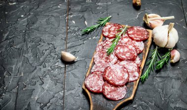 Aromatik baharat ve otlar ile dilimlenmiş salam. Rustik siyah arka plan üzerine.