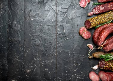 Baharat ve otlar ile farklı salam ürün yelpazesine. Rustik siyah arka plan üzerine.