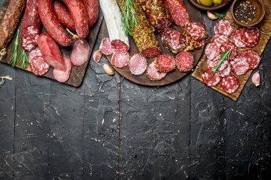 Baharat ve otlar ile farklı salam ürün yelpazesine. Rustik siyah arka plan üzerine.